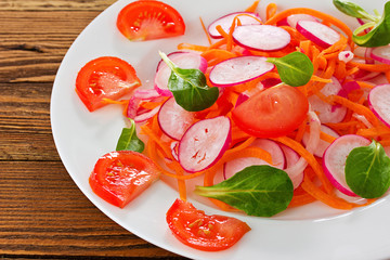 plate with mixed salad on the wooden table