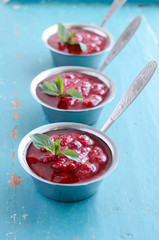 Raspberry sauсe with mint leaf on blue wooden background