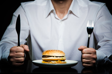 hamburger on a plate in front of a man