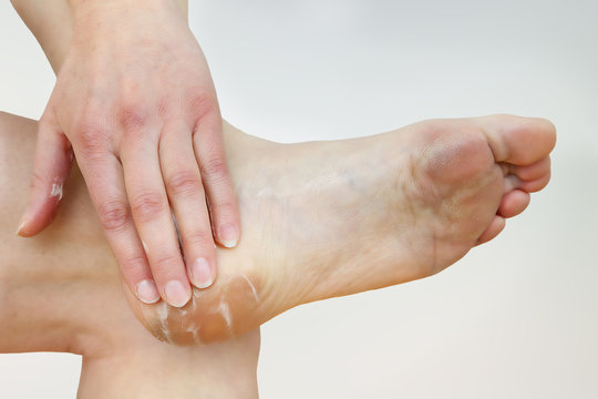A woman putting cream on her foot