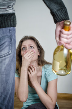 Frightened woman and male hand holding bottle of wine