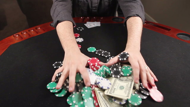 A gambler at a poker table puts his cards down and bets everything he has.