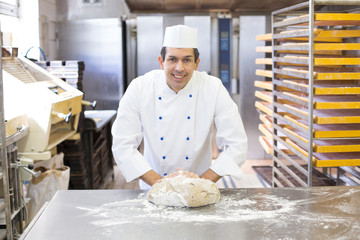 Baker kneading dough in bakery