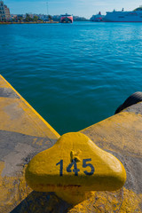 Greece Piraeus,Yellow rusty metal bollard and ship rope harbor a © korpithas