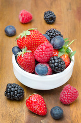 Fresh berries in a bowl on a wooden background