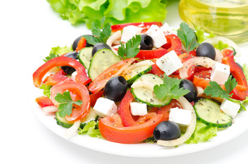 Greek salad with feta cheese, olives and vegetables on white