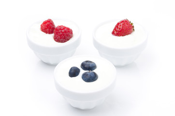 yogurt with different fresh berries in bowls on white