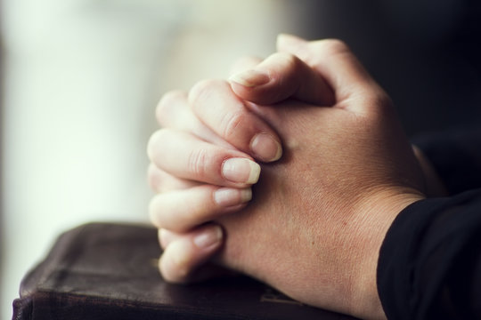 Folding Hands over a Bible