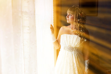 sunlight beautiful young bride is at a wedding in the room by wi