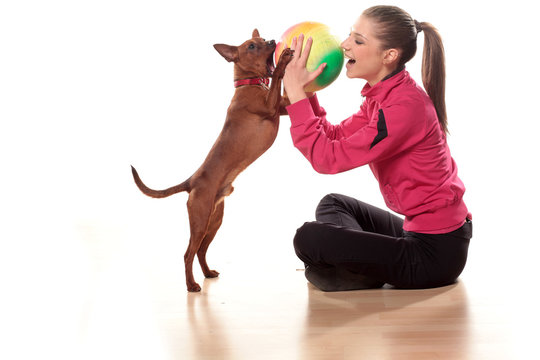 girl in tracksuits playing with a dog and a ball