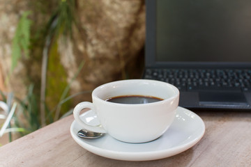 Coffee cup and laptop in garden