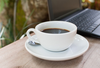 Coffee cup and laptop in garden