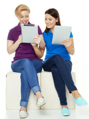 Two girls learning together with touchpad for school
