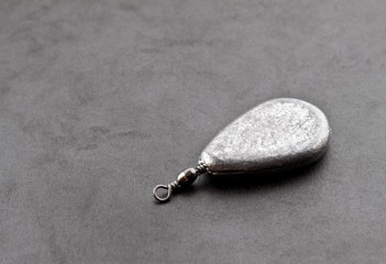 A fishing sinker on dark background with shadow.