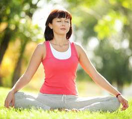Pretty woman doing yoga exercises in the park