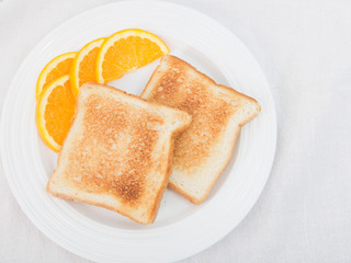 Unbuttered toast on white plate garnished with orange slices
