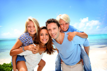 Parents giving piggyback ride to kids at the beach © goodluz