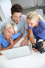 Man with teenagers looking at pictures on computer