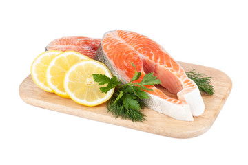 Salmon steaks on cutting board with lemons and herbs