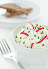 Cottage white cheese in a bowl with radish and chives