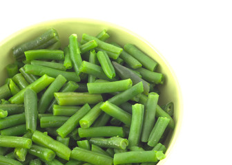 Green beans in green round bowl isolated over white close up