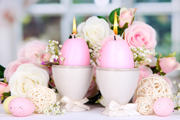 Easter candles with flowers on window background