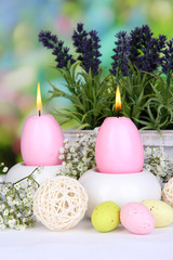 Fototapeta na wymiar Easter candles with flowers on bright background