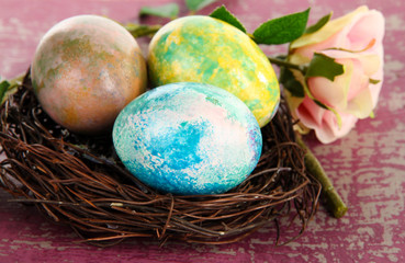 Easter eggs in nest on pink background