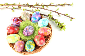 Beautiful Easter eggs in wicker basket isolated on white