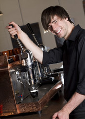 a barista smiles at the camera while brewing an espresso
