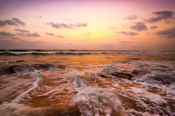 Fototapeta na wymiar Sunset at tropical beach. Ocean sandy coast under evening sun