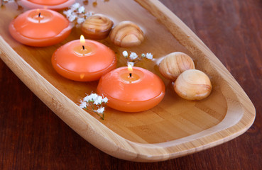 Beautiful candles in water on wooden table close-up