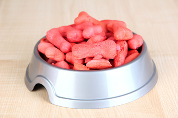 Dry dog food in bowl on wooden background