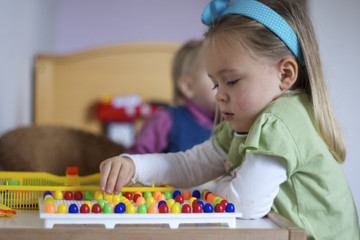 Mädchen spielt Perlen Steckspiel