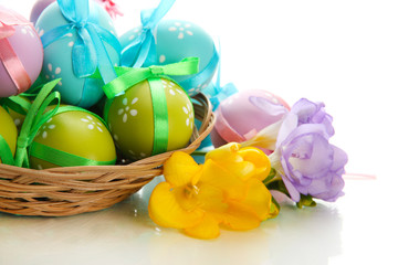 Obraz na płótnie Canvas Bright easter eggs with bows in basket, isolated on white