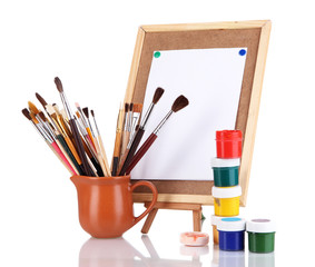 Small easel with sheet of paper and art supplies isolated