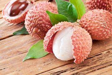 Lychee with leaves on a wooden table.
