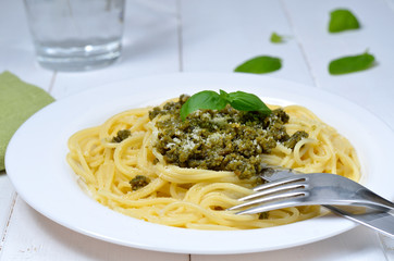 Pasta with pesto sauce and fresh basil on white plate