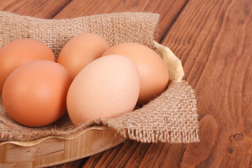 fresh brown chicken eggs in a basket on a sacking