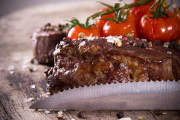 Delicious beef steaks with knife on wooden table