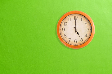 Clock showing 5 o'clock on a green wall