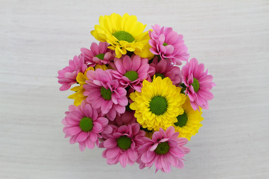 Yellow and pink Santini flower bouquet on white wood
