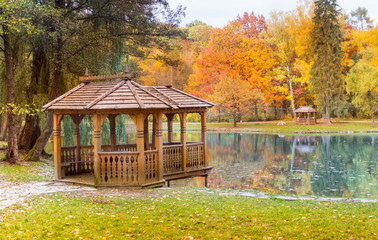 wooden gazebo on the lake in the autumn park