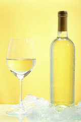 vino bianco freddo con bicchiere e bottiglia su sfondo giallo