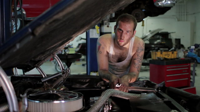 Portrait of a man working on a classic car, wide shot
