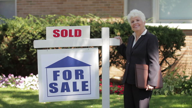 Real estate agent in front of a sold house
