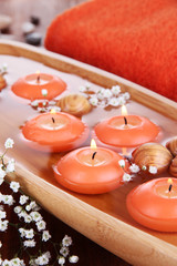 Beautiful candles in water on wooden table on natural