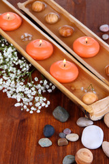 Beautiful candles in water on wooden table close-up