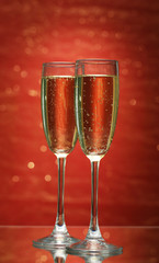 Two glasses of champagne on bright background with lights
