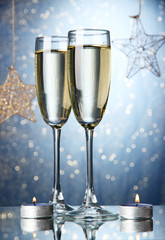 Two glasses of champagne on bright background with lights